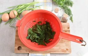 We put the nettle in a colander or sieve and let the water drain. Now it is already possible to cut, it no longer burns.