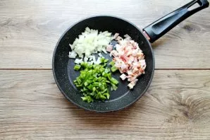 Finely chop the onion, remove the stalk and seeds of the peppers, chop finely, cut the bacon into pieces. Put vegetables and bacon in a pan.