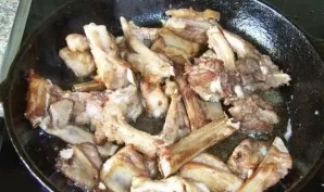 Put the pan on the fire, heat the vegetable oil in it. Place the ribs in the hot oil and cook for 10-12 minutes, stirring with a spatula.