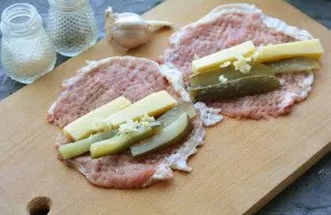 Place pieces of cucumber and cheese on the meat, add some chopped garlic to taste.