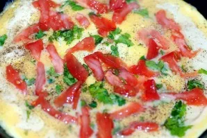 When the bottom of the omelet has set, add the diced tomato and bell peppers. Bake for 3-4 minutes under the lid.