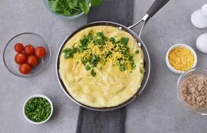 When the omelet thickens on top, sprinkle with grated cheese, chopped onions and spinach (half of everything).