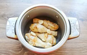 Place the fried drumsticks in a deep pot and add chopped garlic.