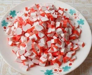 Peel crab sticks or crab meat from cellophane, cut into pieces: cut each stick lengthwise into 2-4 parts, then cut crosswise.