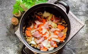 Add half of the chopped onion and 100 grams of chopped smoked meat.