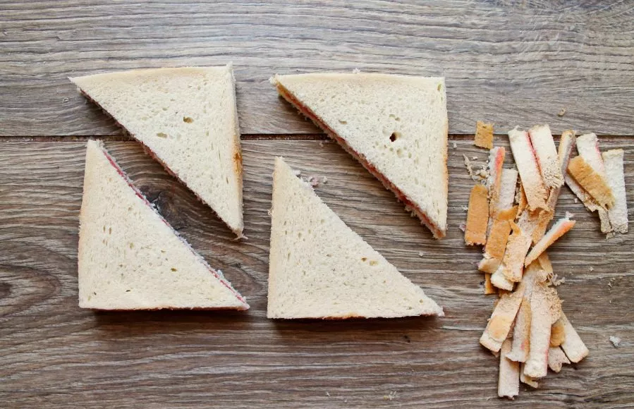 Cut off the edges of the bread and cut diagonally into two triangles.