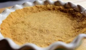 Put the crumbs in a heat-resistant form and form a crust. Place in the oven for 5-7 minutes.