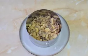 To lay a second layer of canned champignons, cut into pieces.
