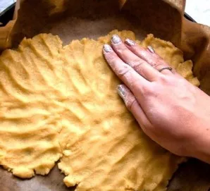 Next, we start shaping the resulting dough in the baking dish with our hands. Before that, fill the form with baking paper.