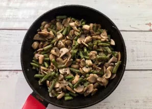 Fry the mushrooms with beans until fully cooked.