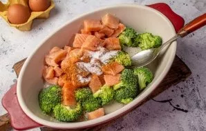 Grease the baking sheet with oil, add the fish and broccoli. Add salt and pepper, stir.