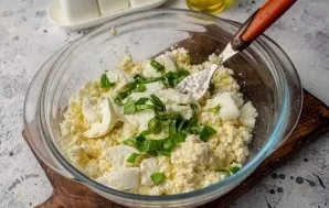 Remove the ball of mozzarella cheese from the whey, tear it into pieces and add it to the curd mass. Cut the basil leaves into thin strip...