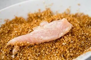 Roll the prepared chicken pieces in sesame seeds.