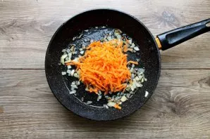Put grated carrots in a pan with onions.