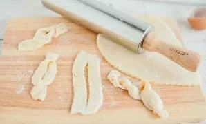 Roll out the dough very thinly - up to half a centimeter. Cut into strips, strips into pieces, make an incision in the center of each, pi...