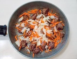 Peel and chop the onion. Add to the pan next to the meat with the carrots.