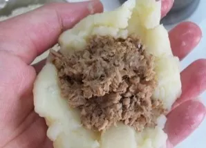 Moisten your hands with cold water, take some mashed potatoes, put the minced meat filling in the middle and make a meatball so that the ...