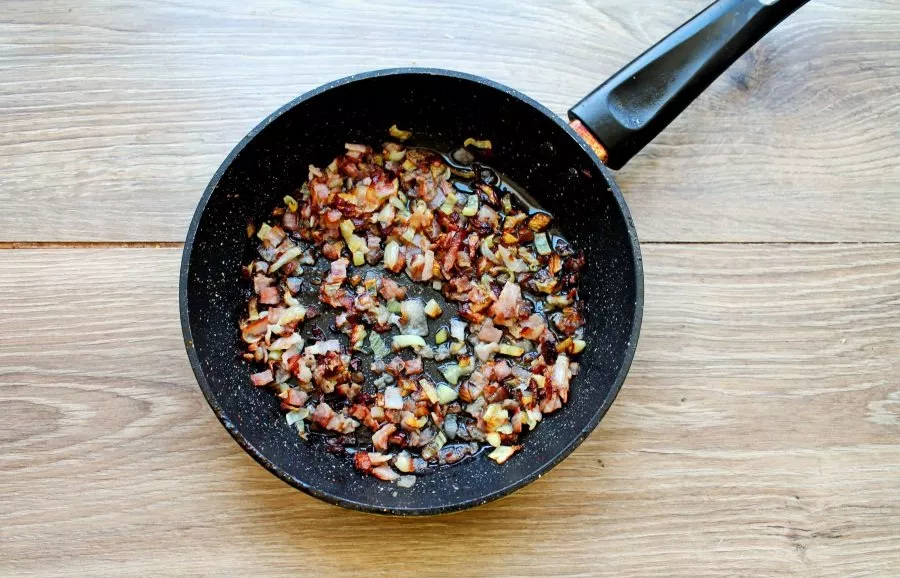 Finely chop the bacon, put it in the pan. Add the finely chopped onion and stir-fry for 5-7 minutes. Remove from heat and let cool slightly.