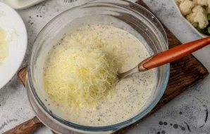 Add 100 grams of grated cheese to the egg-cream mass. Stir.