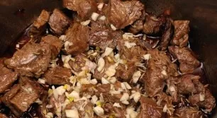 We transfer the meat to a saucepan with onions, add cumin and garlic. Pour water and simmer over low heat under the lid for 2 hours.