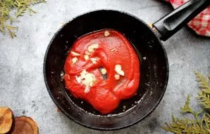 After cooking the minced meat, add tomato paste and chopped garlic to the pan and, stirring, fry for 3-4 minutes.