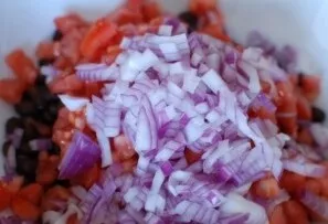 Finely chop the red onion and add to the tomatoes and beans.