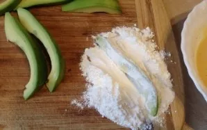 Put the remaining flour on the board, mix with a pinch of salt. Roll the avocado pieces on all sides in the flour.