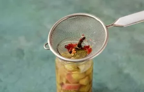 Strain the hot marinade and pour it into the jar.