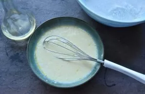 Pour kefir and vegetable oil into the eggs, stir the mass with a whisk.