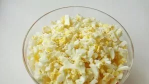 Cool the eggs and peel them. Set aside 2 yolks (serving to decorate the salad), chop.