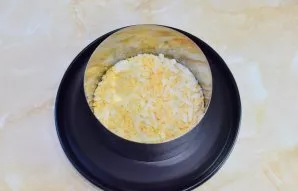 We will lay out the salad in layers. Put a serving ring on a plate and put grated eggs in the first layer. Grease this layer and others w...