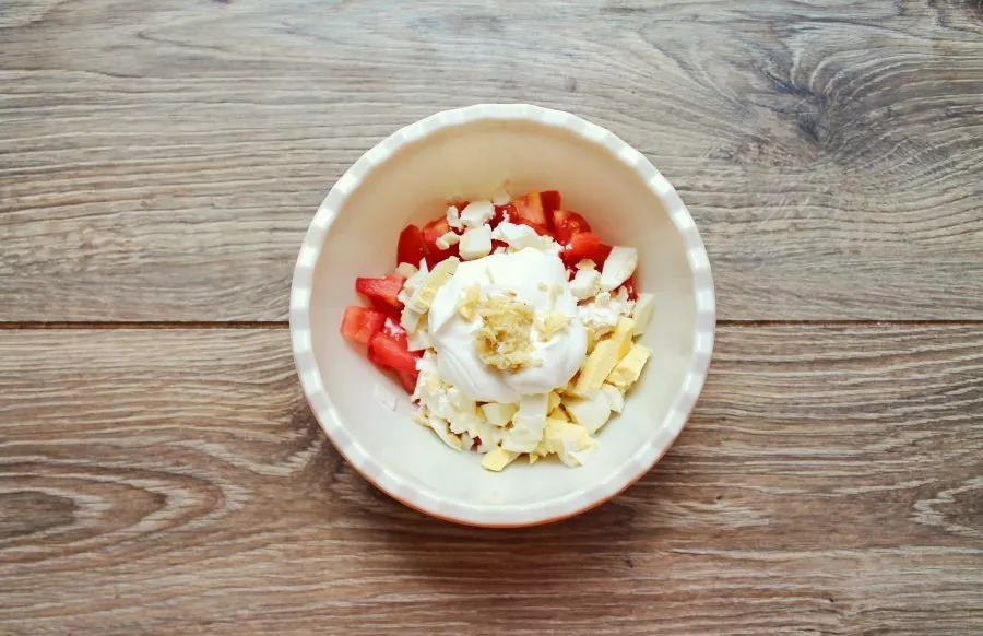 Add sour cream and add chopped garlic. Salt the salad and mix.