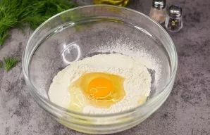 Add wheat flour to a deep bowl, add a pinch of salt and beat the egg.
