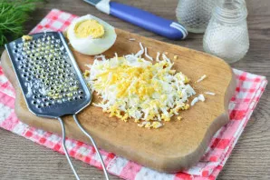 Boil the eggs hard, cool and peel. Grate with a fine grater.