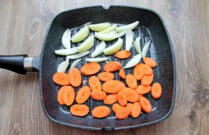 Peel the carrots and cut them into slices. Place on the other side of the pan.