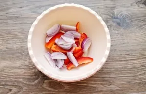 Peel the red onion and cut it lengthwise into 6-8 parts. Add to the pepper in a bowl.