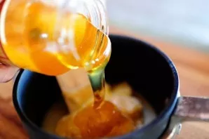 While baklava is baking, we will make syrup for it. We put butter in a saucepan and pour honey.