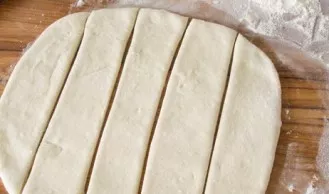 Divide the dough into 2 parts, then roll them into 7-8 mm thick layers. Cut each layer into strips.