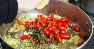 Add tomatoes, herbs and spices with chili peppers to the remaining onions. Sprinkle with lemon juice