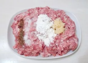 Add salt, starch and ground pepper to the minced meat with garlic.