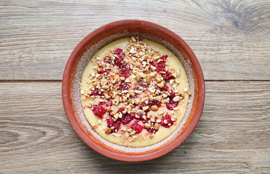 Grease a 16-centimeter diameter baking dish with vegetable oil and pour half of the dough, smooth it out. Top with raspberries and half o...