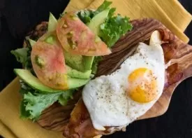 Put an egg on the bacon and slices of tomatoes on top of the salad.