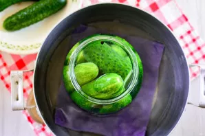 Place a piece of clean cloth on the bottom of a large pot, pour 2 liters of water and heat slightly. Put jars with cucumbers in a saucepa...