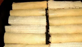 Mix the two parts of the sauce. Add chopped garlic. Roll waffle cakes into rolls. Put in a baking dish.