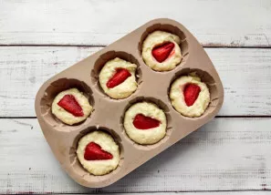 Put the dough in muffin forms, put a small strawberry wedge inside and put it in the oven heated to 180 degrees for 30 minutes.