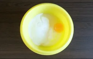 Make the filling. Pour sour cream into a bowl, add an egg and 150 grams of sugar. Mix it up.