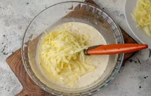 Add 100 grams of grated cheese. Mix it with the egg-cream mass.