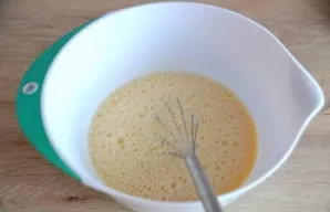 While stirring, pour the warmed milk over the beaten eggs.