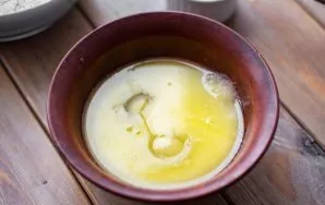 Pour melted and slightly cooled butter (80 grams) into a separate bowl, add the remaining white sugar and eggs.