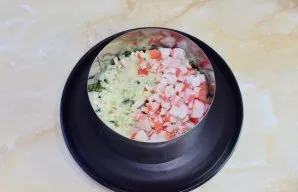 Then put a layer of finely chopped cucumbers and a layer of crab sticks.